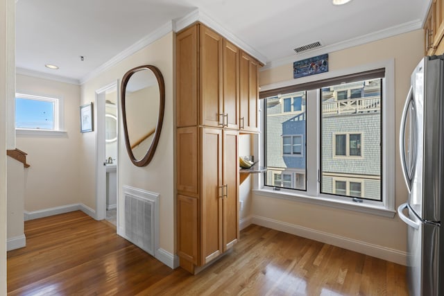 kitchen with stainless steel refrigerator, crown molding, hardwood / wood-style floors, and a healthy amount of sunlight