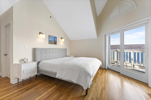 bedroom featuring hardwood / wood-style floors, access to outside, and lofted ceiling