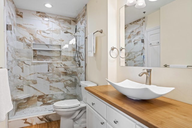 bathroom with tiled shower, vanity, hardwood / wood-style flooring, and toilet