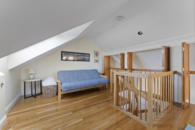 sitting room featuring lofted ceiling with skylight and hardwood / wood-style floors