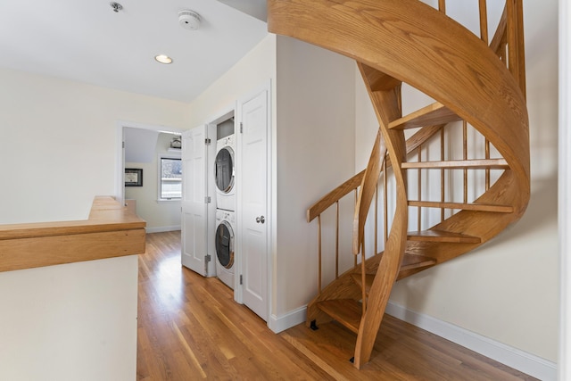 clothes washing area featuring hardwood / wood-style flooring and stacked washer / dryer