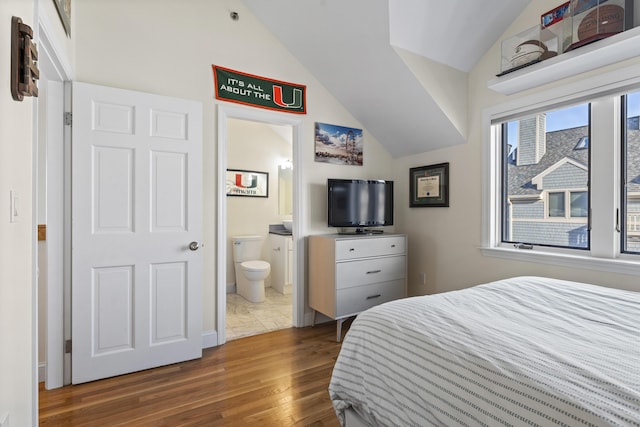 bedroom featuring ensuite bathroom, wood-type flooring, and vaulted ceiling