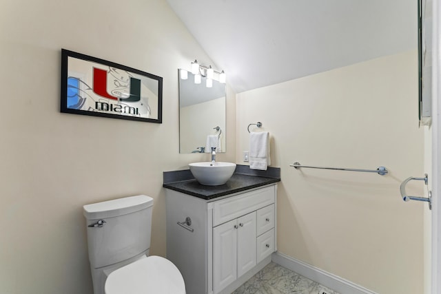 bathroom with vanity, toilet, and lofted ceiling