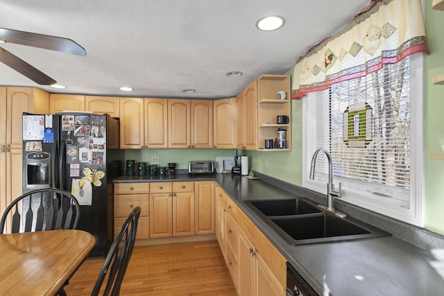 kitchen with sink, light hardwood / wood-style flooring, a textured ceiling, light brown cabinetry, and black appliances