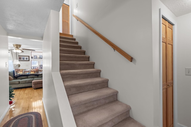 staircase with hardwood / wood-style flooring, ceiling fan, and a textured ceiling