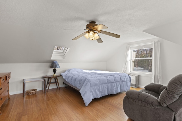 bedroom with vaulted ceiling, ceiling fan, hardwood / wood-style floors, and a textured ceiling