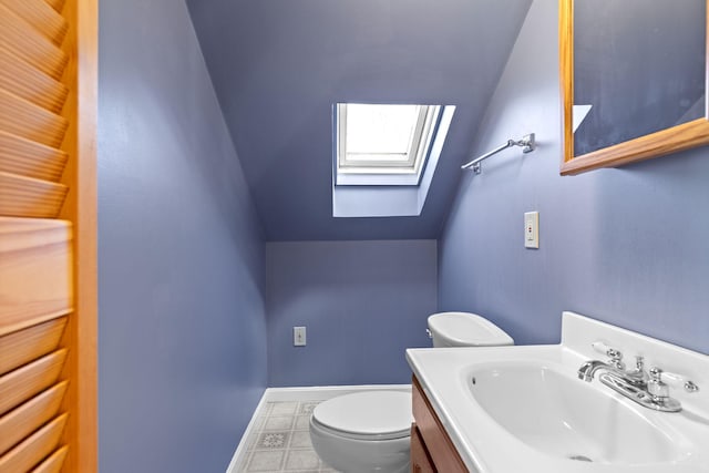 bathroom featuring vanity, toilet, and vaulted ceiling with skylight