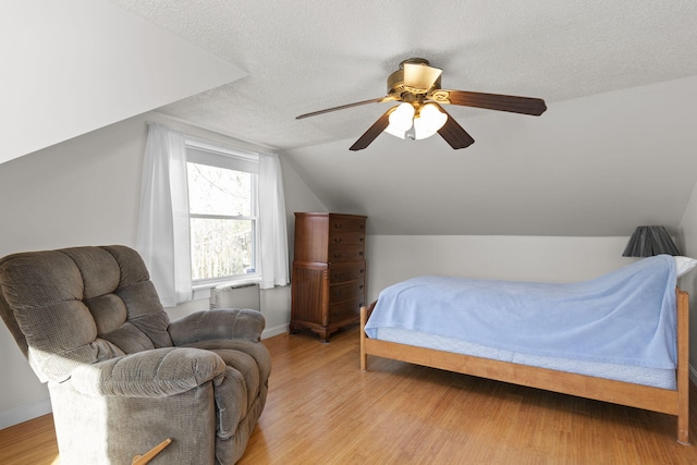 bedroom featuring ceiling fan, light hardwood / wood-style floors, and a textured ceiling