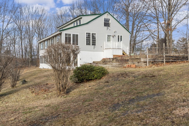 rear view of property featuring a lawn and a sunroom