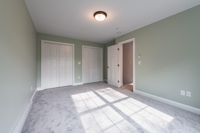 unfurnished bedroom with light carpet and two closets