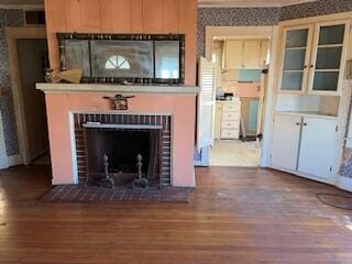 unfurnished living room featuring hardwood / wood-style floors and a brick fireplace