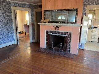 unfurnished living room featuring dark hardwood / wood-style flooring, ornamental molding, and a brick fireplace