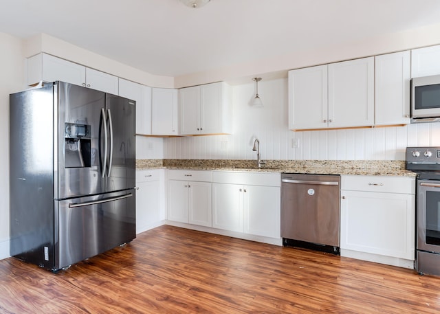 kitchen with white cabinets, sink, stainless steel appliances, and hanging light fixtures