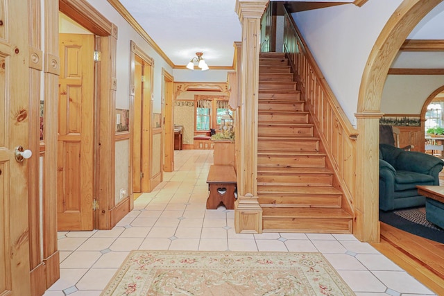 stairs featuring arched walkways, ornamental molding, tile patterned floors, and a healthy amount of sunlight