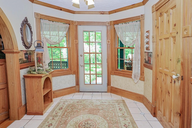 doorway with wallpapered walls, a textured ceiling, crown molding, and light tile patterned flooring