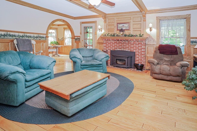 living area featuring arched walkways, a wainscoted wall, wood finished floors, ornamental molding, and a wood stove