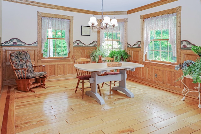 dining room featuring ornamental molding, a wealth of natural light, a wainscoted wall, and light wood-style flooring