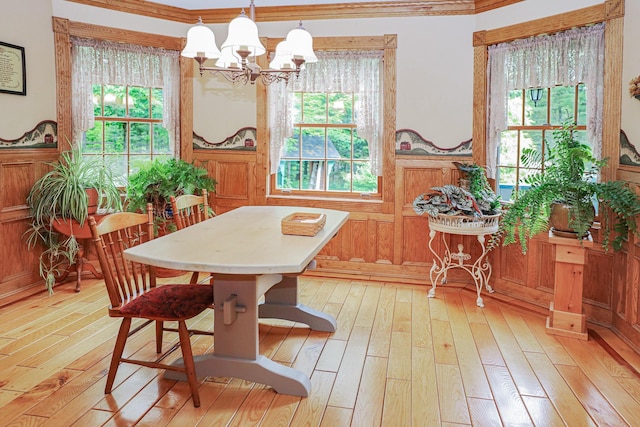 dining room with a chandelier, ornamental molding, and light wood-style flooring