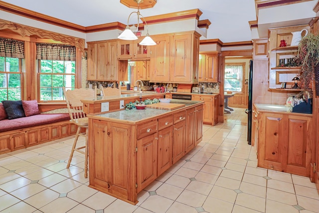 kitchen featuring decorative light fixtures, a breakfast bar area, light countertops, ornamental molding, and a kitchen island