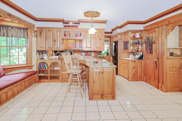 kitchen featuring crown molding, light countertops, a breakfast bar, and a healthy amount of sunlight