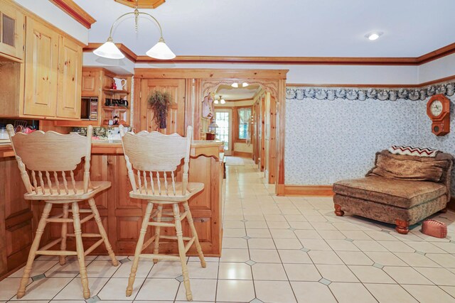 kitchen with wallpapered walls, arched walkways, a breakfast bar, crown molding, and light brown cabinets