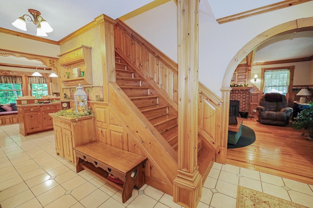 stairway featuring arched walkways, crown molding, an inviting chandelier, wainscoting, and tile patterned floors