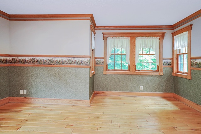 empty room with wood-type flooring, wainscoting, crown molding, and wallpapered walls