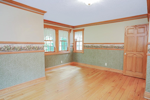 empty room with wallpapered walls, baseboards, crown molding, a textured ceiling, and light wood-style floors