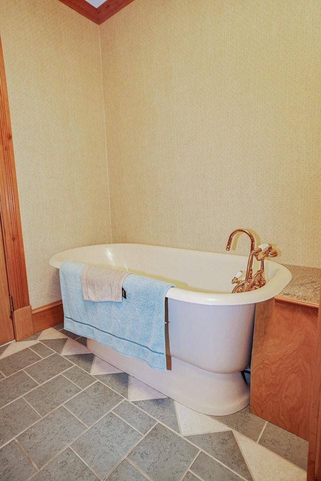 bathroom featuring a soaking tub, wallpapered walls, and stone tile flooring