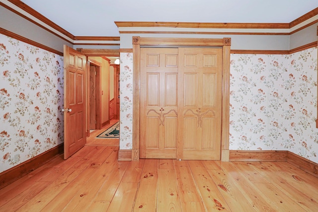 unfurnished bedroom with crown molding, light wood-type flooring, baseboards, and wallpapered walls