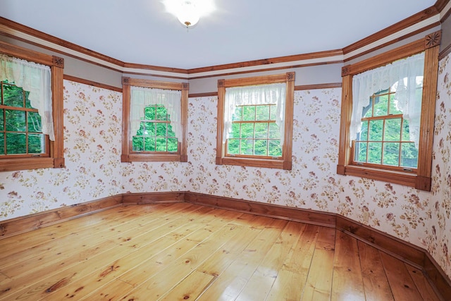 unfurnished room featuring baseboards, light wood finished floors, and wallpapered walls