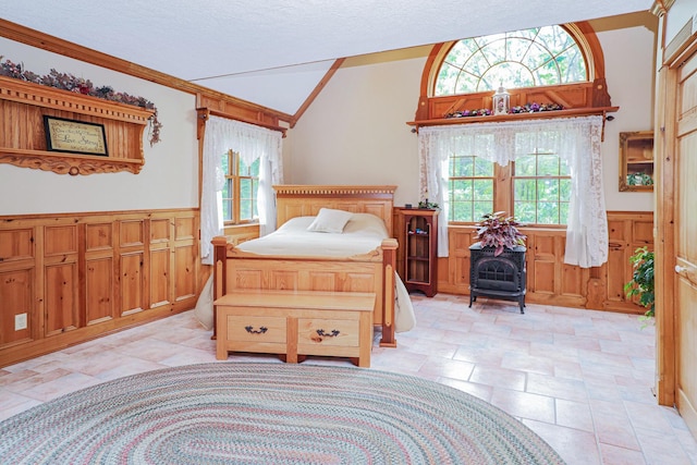 bedroom featuring a wainscoted wall, a textured ceiling, vaulted ceiling, and crown molding