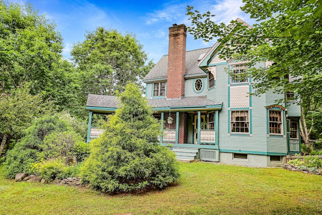 victorian-style house with a shingled roof, a front yard, covered porch, and a chimney