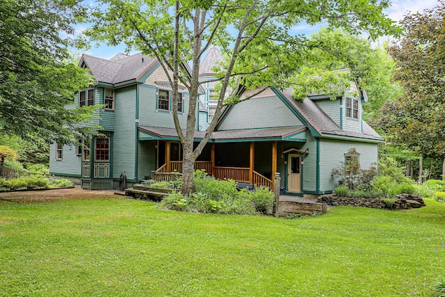 view of front of house with covered porch, a shingled roof, and a front yard