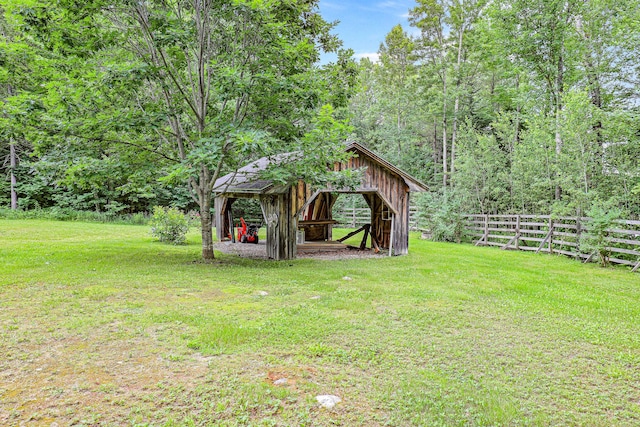 view of outdoor structure featuring a wooded view, fence, and an outdoor structure