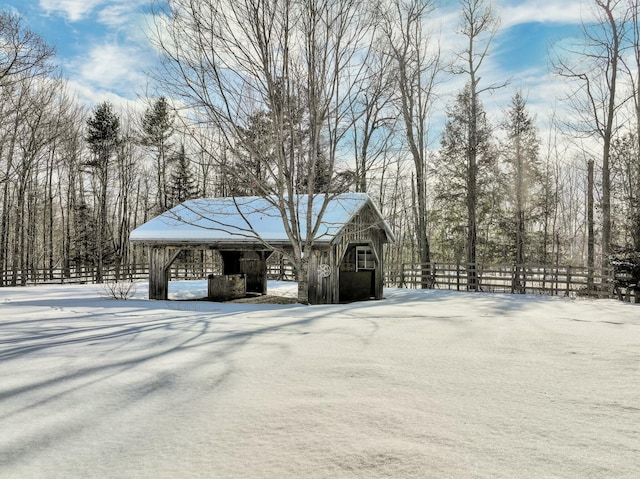 snow covered structure with a barn, fence, and an outdoor structure