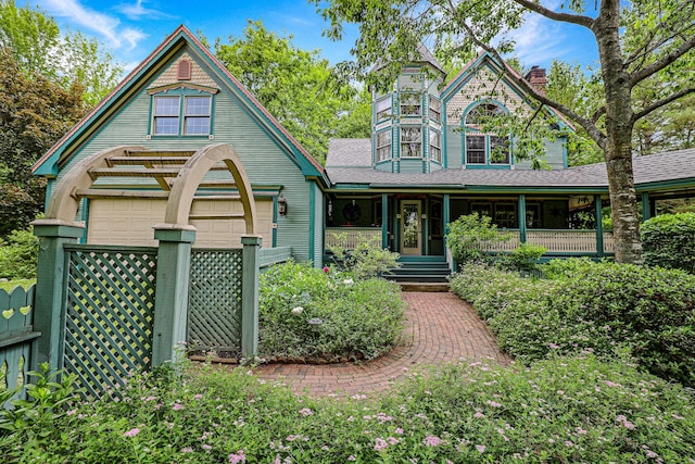 view of front of home featuring covered porch, a chimney, a garage, and roof with shingles
