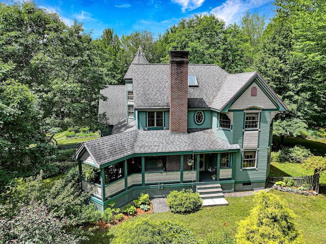 victorian home featuring a porch, a front lawn, a shingled roof, and a chimney