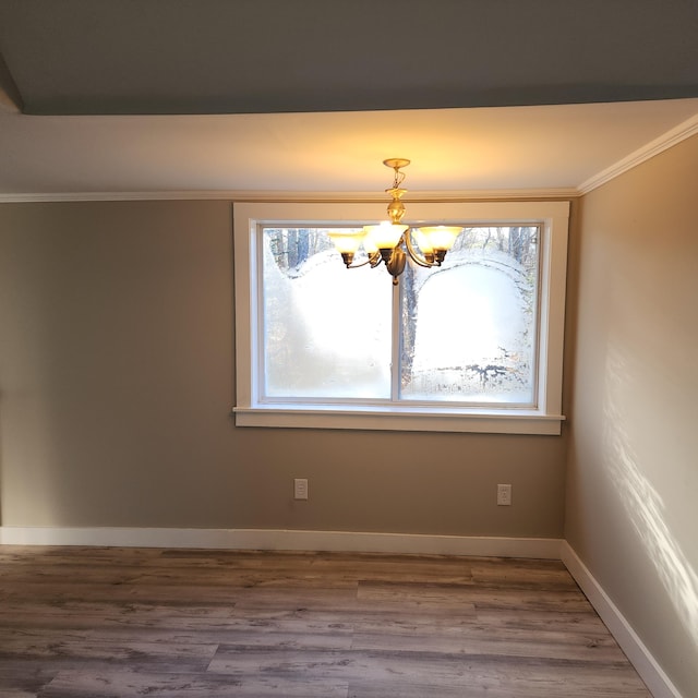 unfurnished dining area featuring wood-type flooring, crown molding, and a notable chandelier