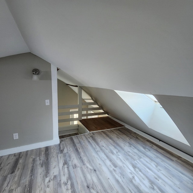 bonus room featuring vaulted ceiling with skylight and light hardwood / wood-style floors