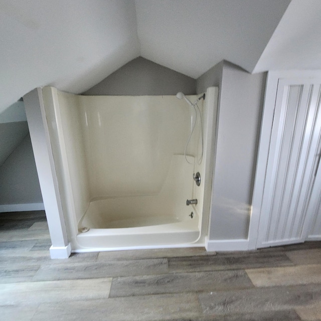 bathroom with hardwood / wood-style floors, lofted ceiling, and shower / tub combination