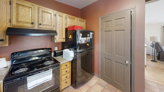 kitchen with a baseboard heating unit, light tile patterned floors, light brown cabinets, and black appliances