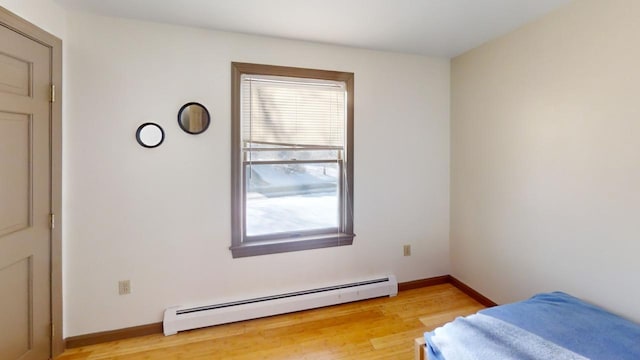 bedroom with a baseboard heating unit and light hardwood / wood-style floors