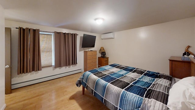 bedroom with hardwood / wood-style flooring, a baseboard radiator, and an AC wall unit