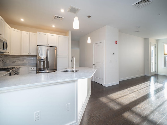 kitchen with pendant lighting, white cabinets, sink, appliances with stainless steel finishes, and light stone counters