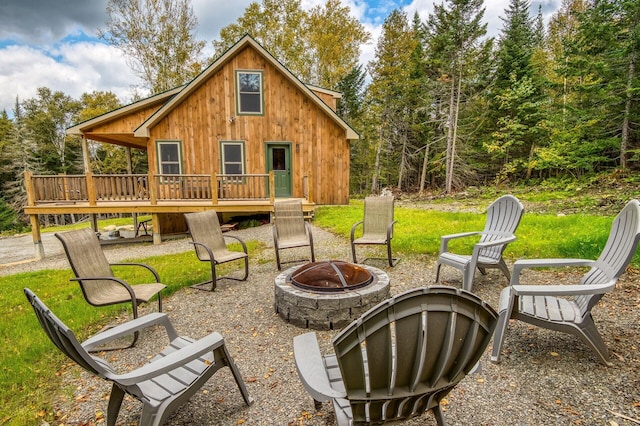 rear view of house with a wooden deck and an outdoor fire pit