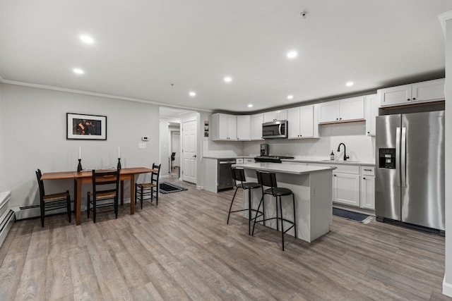 kitchen with a kitchen bar, white cabinetry, sink, and appliances with stainless steel finishes