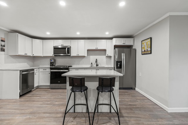 kitchen with stainless steel appliances, white cabinetry, and crown molding