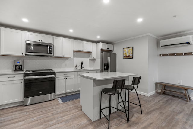 kitchen with white cabinets, sink, an AC wall unit, and stainless steel appliances