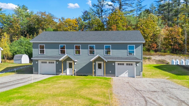 view of front of home with a storage unit, a garage, and a front lawn